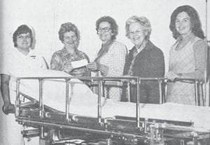 The North Shore Hospital received a new “Surgibed” table for the emergency room from the hospital auxiliary on March 4, 1976. The bed has many features and can be used as a surgical table, transport-stretcher, and recovery bed. Shown presenting the check, from left, are Vera Flavell, LPN in charge of the emergency room; auxiliary treasurer Nancy Lindquist; Alma Adams, hospital administrator; past auxiliary president June Olson; and current auxiliary president Donna Clothier.