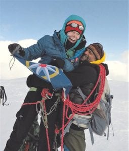 Pascale Marceau, from Canmore, Alta., holding The Royal Canadian Geographical Society expedition flag alongside fellow explorer Lonnie Dupre, from Minnesota, celebrating on the summit of Jeannette Peak.