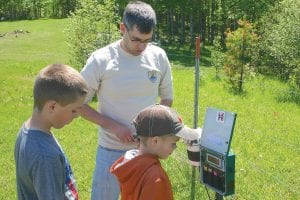 Oscar and Ty Mielke watched as U.S. Fish & Wildlife Biologist Kevin Heist changed the batteries on an ultrasonic device last Tuesday. The ultrasonic detector is used to pick up the sounds of bats and birds as they migrate. The Mielke brothers and cousin Reuben Youngdahl were at their grandparent’s farm the day the biologists came to do maintenance on Merlin, the avian radar system, and the gear associated with it.