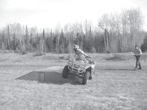 A young Cook County ATV rider learns to navigate a banked slope under the watchful eye of a local instructor. ATV riders are asked to wear their helmets and follow safety rules when they drive their ATVs on trails or on a road where it is allowable to ride. While it’s fun to operate an ATV, safety is the first prerogative of a driver.