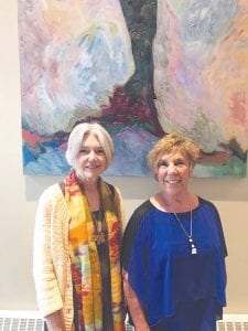 New art graces the new walls in the halls of North Shore Health. On the left, Lynn Anderson and Susan Hildebrand, Ade Toftey’s daughter, recently talked about the new display at the inaugural exhibit.